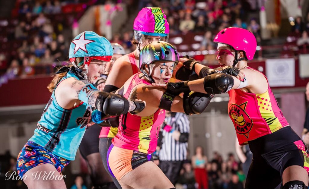 Three Maul Rats skaters in pink block a jammer from Bodies of Water