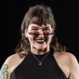 Erma smiling at the camera with black lipstick and flame sunglasses on