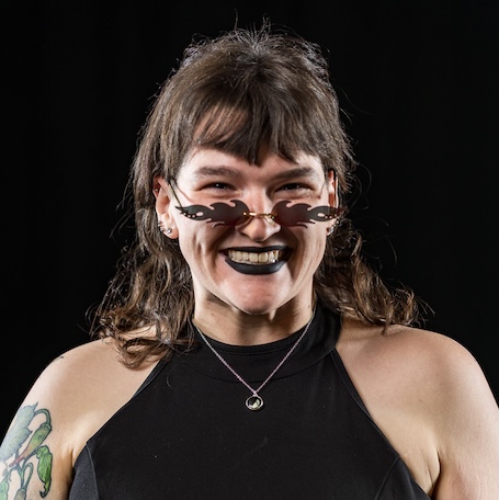 Erma smiling at the camera with black lipstick and flame sunglasses on
