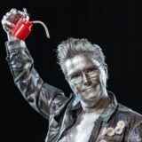 BerNasty covered in silver paint holding an oil can